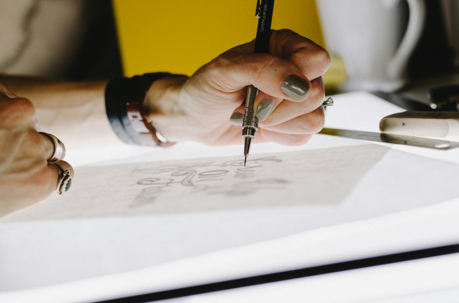 A hand working a pencil across paper, refining a sketch during the construction phase